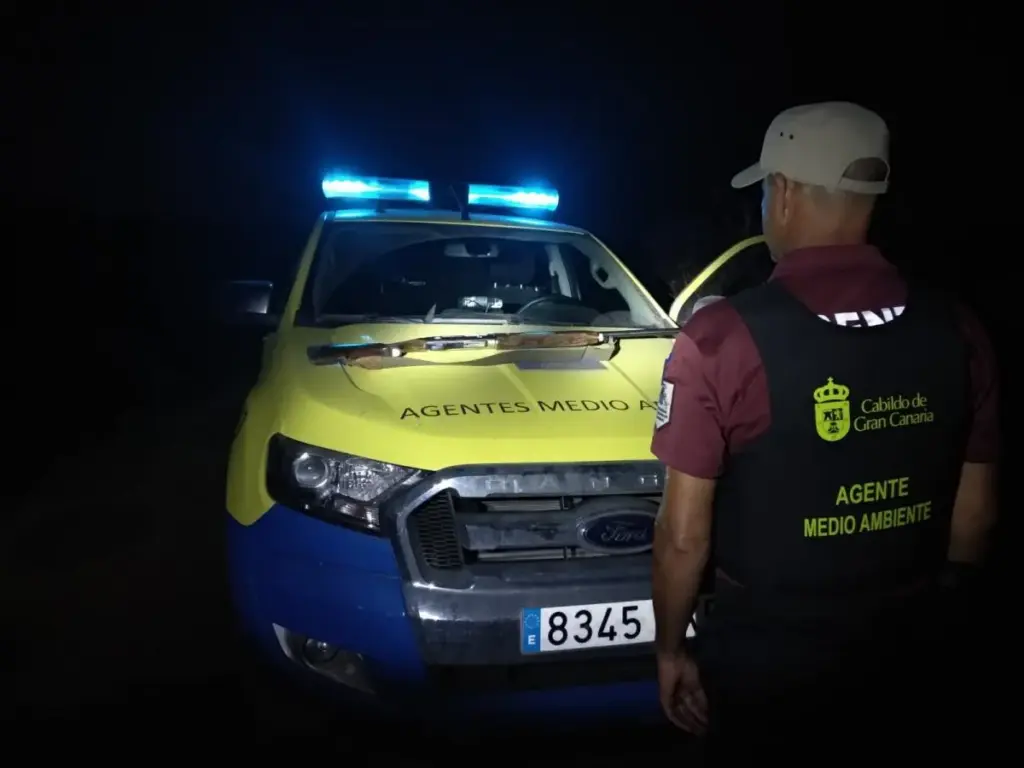 Agente de Medio Ambiente del Cabildo de Gran Canaria junto a un vehículo oficial durante un operativo nocturno