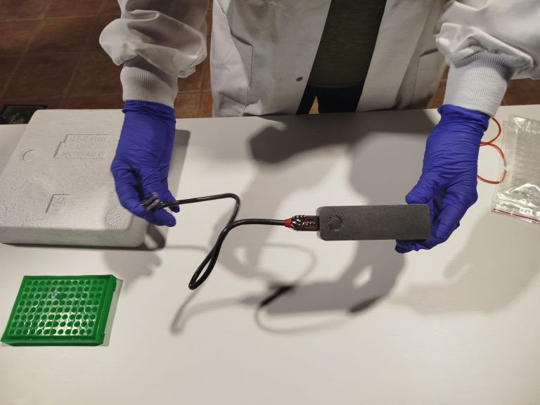 Investigador con guantes usando un dispositivo portátil de análisis genético